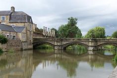 a stone bridge over a river next to tall buildings