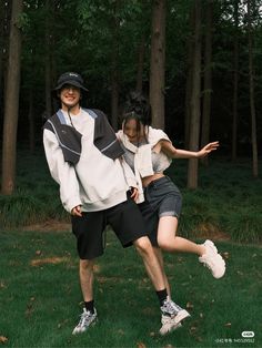 a man and woman are playing with a frisbee in the grass near some trees