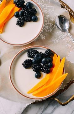 two plates topped with fruit and yogurt on top of a white table cloth