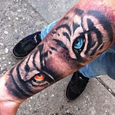 a man's arm with a tiger tattoo on it and an eyeball in the center