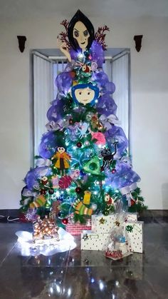 a christmas tree decorated with purple, green and blue ornaments is in the middle of a room