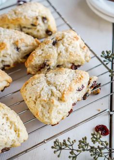 several scones on a cooling rack with cranberries and other pastries nearby