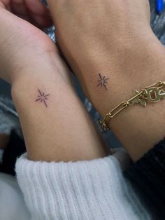 two people with matching tattoos on their arms, one is holding the other's hand