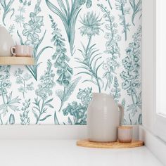 a vase sitting on top of a counter next to a wallpapered with flowers