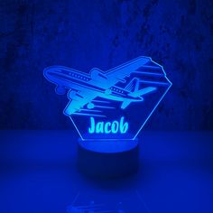 an airplane shaped lamp with the name jacob on it's base in front of a blue background