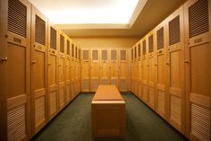 an empty room with several lockers and a bench in the middle is lit by light