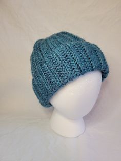 a white mannequin head wearing a blue knitted hat on top of it