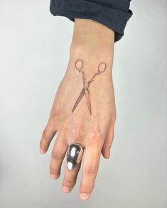 a woman's left hand with a tattoo on it and a pair of scissors