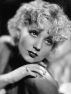 an old black and white photo of a woman with her hand on her chin looking at the camera