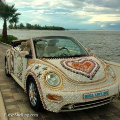 a car decorated with hearts and stars parked next to the ocean