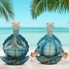 two turtle statues sitting on top of a sandy beach