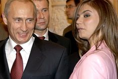 a man in a suit and tie standing next to two women with other people behind him