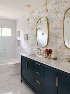 the bathroom is decorated in white and gold with floral wallpaper on the walls, along with two sinks