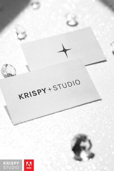 two business cards sitting on top of a table covered in drops of raindrops