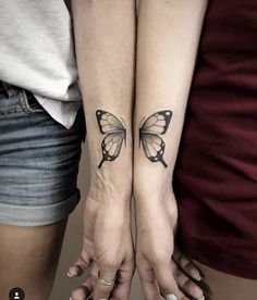 two women with matching tattoos on their arms holding each other's hands and one has a butterfly tattoo on her left arm