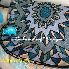 an elephant is sitting on top of a blue and green quilted blanket with geometric designs