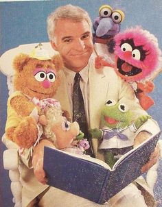 the man is holding an open book with stuffed animals around him and smiling at the camera