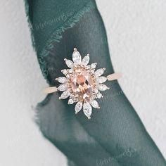 an engagement ring with a pink diamond center surrounded by white and rose cut diamonds on a green napkin