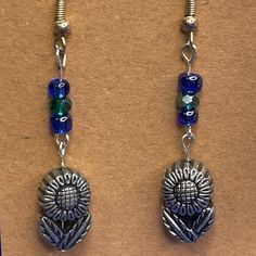 Fun Hippie Flower earrings! Cute silver charm with detail on both sides. Topped with tiny blue beads.