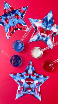 red, white and blue paper stars are arranged on a pink surface with drinks in glasses