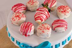 a white plate topped with red and white cake covered in frosted strawberries next to a blue ribbon