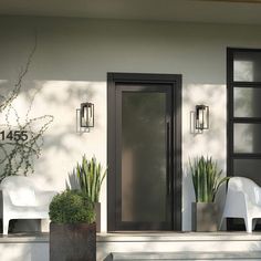 two white chairs sitting on the front steps of a house with black doors and windows