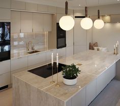 a modern kitchen with marble counter tops and lights hanging from the ceiling over the sink