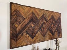 a wood paneled wall hanging on the side of a wall next to a potted plant