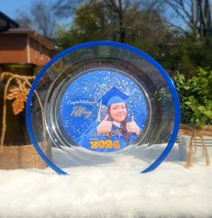 a glass plate with a photo of a graduate on it sitting in the middle of snow