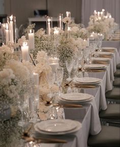 a long table is set with white flowers and candles for an elegant dinnereone