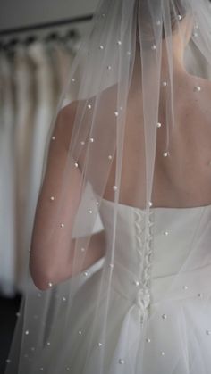 the back of a bride's wedding dress, with pearls on it and veil