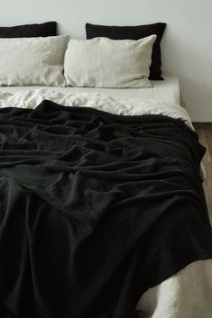 a bed with black and white linens on top of it in a small room