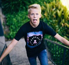 a young boy making a funny face while walking up stairs with his hands in the air