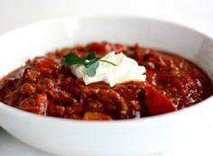 a white bowl filled with chili and sour cream