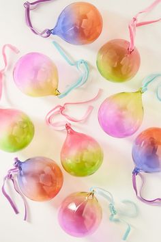 several different colored glass ornaments on a white surface with ribbons around them and tied together