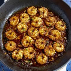 cooked shrimp in a skillet on top of a blue countertop next to utensils