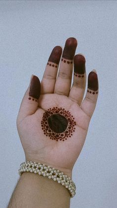 a woman's hand with henna tattoos on her left wrist and the palm of her right hand