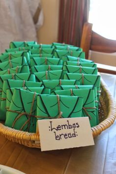 a basket filled with lots of green paper wrapped in twine on top of a table