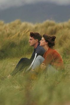 two people are sitting in the tall grass