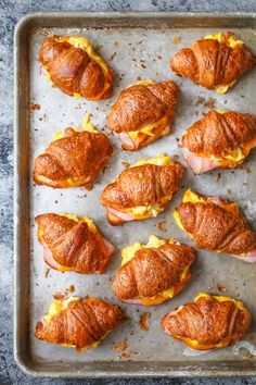 croissants with ham and cheese are on a baking sheet, ready to go into the oven