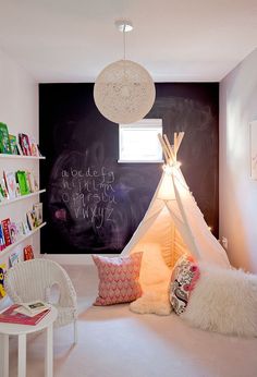 a child's room with a teepee tent and bookshelves on the wall