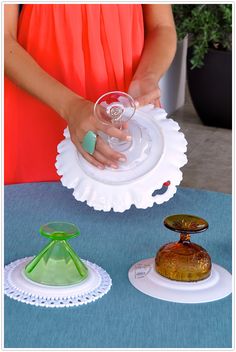 a woman holding a wine glass on top of a plate next to two other dishes