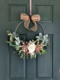 a green door with a wreath and flowers hanging on it's front door handle