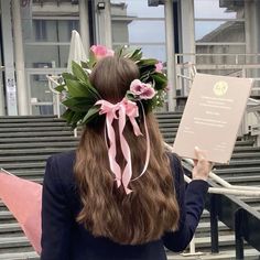 a woman with flowers in her hair holding up a piece of paper