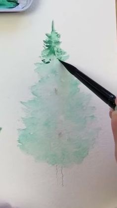 someone is painting a green christmas tree with watercolors