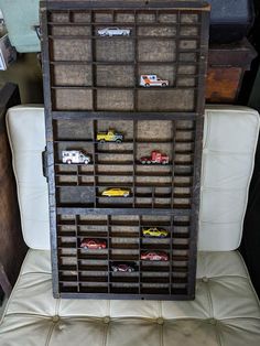 a chair that has some sort of storage on it's backrest with toy cars in the drawer