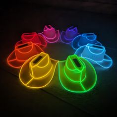 neon hats are arranged in the shape of a circle on a dark surface, with one hat lit up