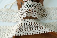 two pieces of white crochet lace on a table