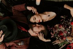 a man and woman laying on the ground next to each other with flowers in front of them