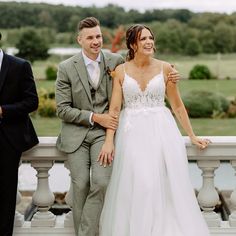 a man and woman standing next to each other on a bridge with trees in the background